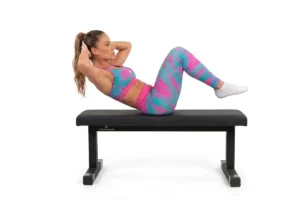 Mujer realizando abdominales tradicionales sobre banco para abdominales plano para fortalecer el abdomen